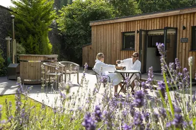two women sitting at a table in a garden at Shepherds Retreat Hutton John in a walled garden in a rural setting only 10 minutes for Lake Ullswater in Penruddock
