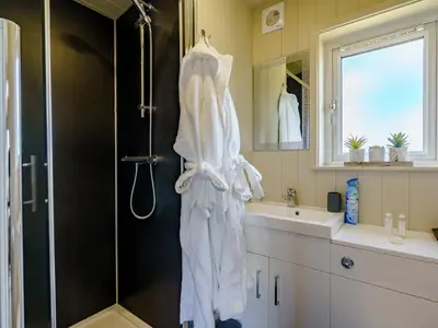 a bathroom with a shower with a robe hanging on the wall at 1 Bed in Turnberry 78071 in Girvan