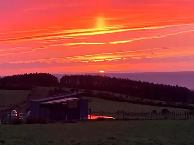 a sunset over a field with a barn in the foreground at 1 Bed in Turnberry 78071 in Girvan