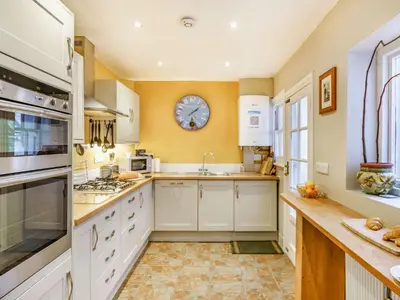 a kitchen with white cabinets and a clock on the wall at 3 Bed in Keswick 86162 in Keswick