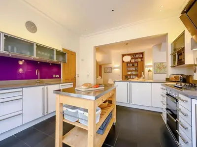 a large kitchen with white cabinets and purple walls at 4 Bed in Keswick oc-89258 in Keswick