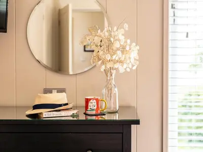 a vase of flowers on a table with a mirror at 2 Bed in Caldbeck 80563 in Caldbeck