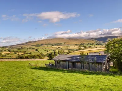 an old house in a field with hills in the background at 2 Bed in Caldbeck 80563 in Caldbeck