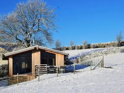 a small cabin in the snow with a tree at 2 Bed in Caldbeck 80563 in Caldbeck