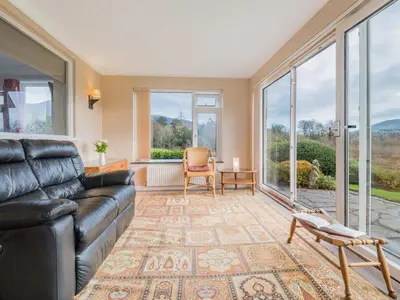 a living room with a leather couch and large windows at 2 Bed in Portinscale SZ071 in Portinscale