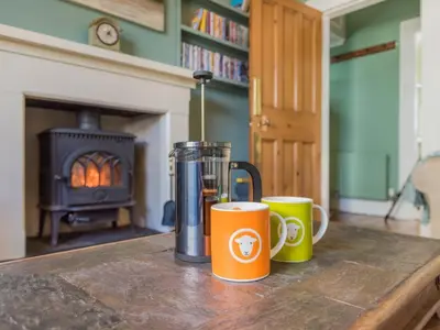 two coffee mugs sitting on a wooden table in front of a fireplace at 2 Bed in Keswick oc-sz126 in Keswick