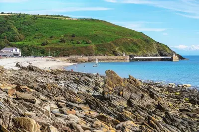 a beach with a train on a hill next to the water at The Cottage, Bridge House in Laxey