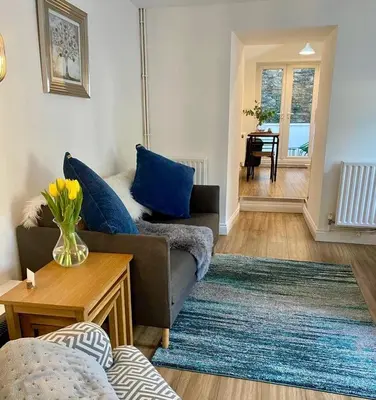 a living room with a couch and a table at The Cottage, Bridge House in Laxey