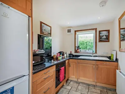 a kitchen with wooden cabinets and a sink at 1 Bed in Balmaclellan CA371 in Castle Douglas