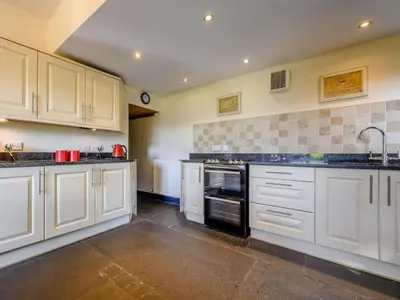 a kitchen with white cabinets and black appliances at 3 Bed in Eskdale SZ072 in Santon Bridge