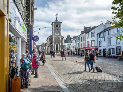a group of people walking down a street with a church at 3 Bed in Keswick oc-sz446 in Portinscale