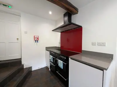 a kitchen with a stove and a red cabinet at 6 Bed in Workington oc-sz327 in Lamplugh