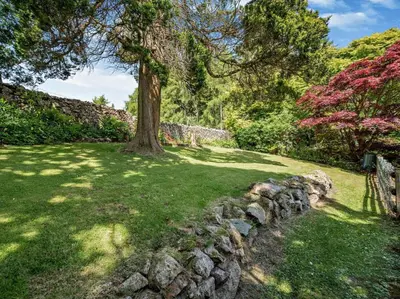 a tree in a yard with a stone wall at 3 Bed in Holmrook oc-sz414 in Santon Bridge