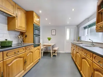 a large kitchen with wooden cabinets and a table at 6 Bed in Keswick oc-sz389 in Keswick