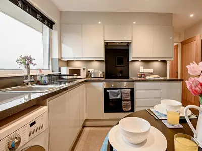 a kitchen with white cabinets and a sink and a table at 2 Bed in Keswick oc-sz116 in Keswick
