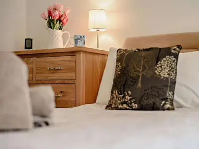 a bed with a pillow and a dresser with flowers on it at 2 Bed in Keswick oc-sz116 in Keswick