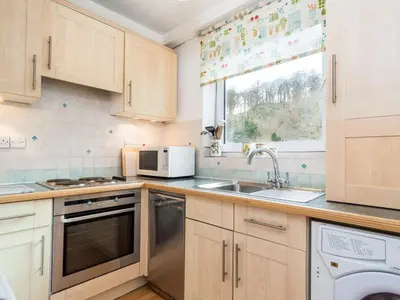a kitchen with wooden cabinets and a sink and a window at 2 Bed in Keswick oc-sz068 in Rosthwaite