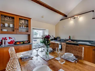 a kitchen with a wooden table with glasses and flowers at 2 Bed in Ravenglass SZ409 in Ravenglass