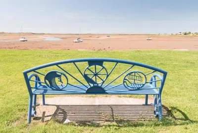 a blue bench sitting in the grass near a beach at 2 Bed in Ravenglass SZ409 in Ravenglass