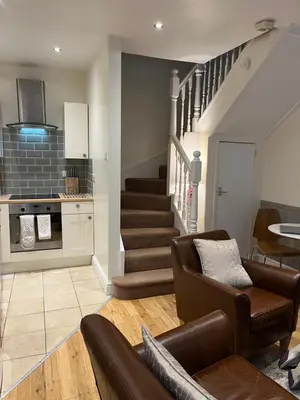 a living room with a couch and a staircase at Daffodil Cottage in Cockermouth