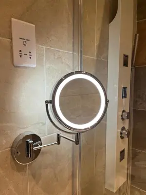 a mirror on the wall of a shower in a bathroom at Daffodil Cottage in Cockermouth