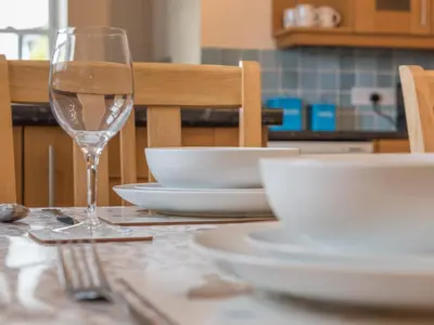 a table with white plates and a wine glass at 2 Bed in Keswick oc-sz490 in Keswick