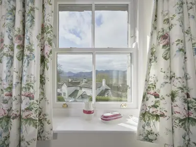 a window with curtains with a view of a house at 4 Bed in Keswick oc-sz434 in Applethwaite