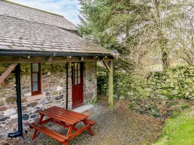 a wooden picnic table in front of a stone building at 2 Bed in Penrith oc-sz339 in Watermillock