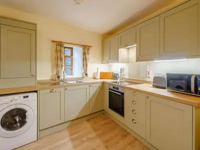 a kitchen with white cabinets and a washing machine at 2 Bed in Penrith oc-sz339 in Watermillock