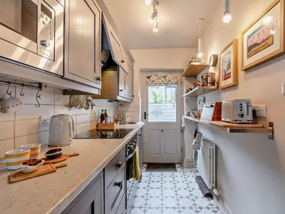 a kitchen with white cabinets and a tile floor at 1 Bed in Keswick oc-sz112 in Keswick