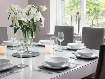 a table with white plates and glasses and a vase of flowers at 4 Bed in Keswick oc-sz219 in Grange