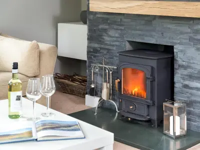 a living room with a fireplace and a table with wine glasses at 4 Bed in Keswick oc-sz219 in Grange