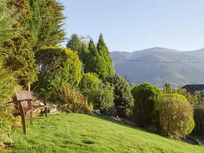 a bench sitting on a grassy hill with mountains in the background at 3 Bed in Keswick oc-sz194 in Braithwaite