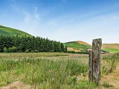 a wooden fence in a field with mountains in the background at 1 Bed in Lorton SZ160 in Lorton