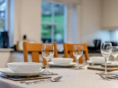 a table with plates and bowls and wine glasses at 3 Bed in Penrith oc-sz247 in Dockray