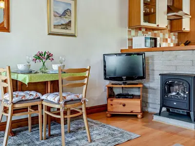 a living room with a table and a television and a fireplace at 2 Bed in Keswick oc-sz145 in Braithwaite