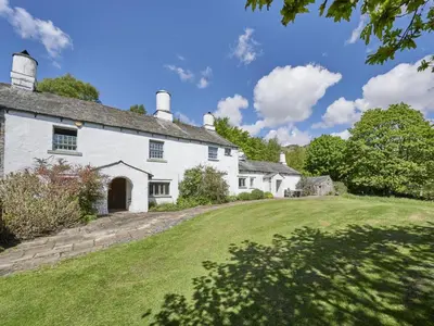 an exterior view of a white house with a yard at 5 Bed in Holmrook oc-sz259 in Eskdale