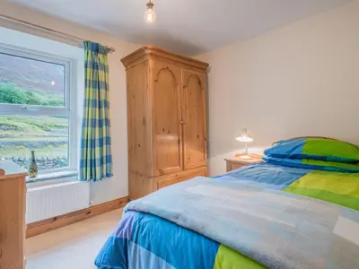 a bedroom with a bed with a wooden cabinet and a window at 3 Bed in Keswick oc-sz227 in Threlkeld