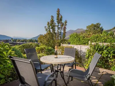 a table and chairs on a patio with mountains in the background at 1 Bed in Keswick oc-sz437 in Keswick