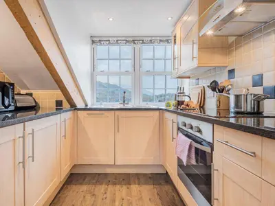 a kitchen with wooden cabinets and a large window at 2 Bed in Keswick SZ494 in Keswick