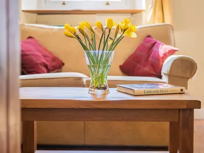 a vase of yellow flowers and a book on a table at 2 Bed in Keswick oc-sz378 in Portinscale