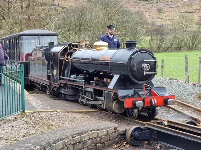 a man driving a small train on the tracks at 2 Bed in Holmrook oc-sz464 in Beckfoot