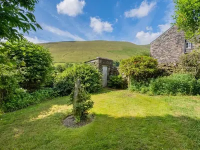 a stone house with a green hill in the background at 2 Bed in Penrith oc-sz218 in Mosedale