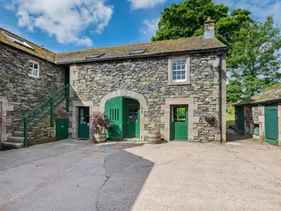 an old stone building with green doors and a driveway at 2 Bed in Penrith oc-sz218 in Mosedale