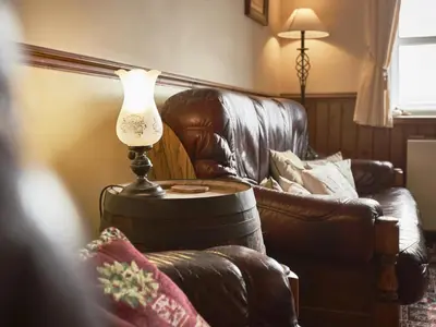 a lamp on a table next to a leather couch at 2 Bed in Wasdale Head oc-sz551 in Nether Wasdale