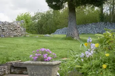 a garden with flowers and a stone wall and a tree at 1 Bed in Eskdale SZ471 in Beckfoot