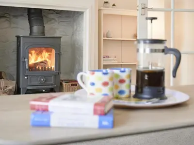 a table with a book and a cup of coffee and a stove at 3 Bed in Keswick oc-sz533 in Braithwaite