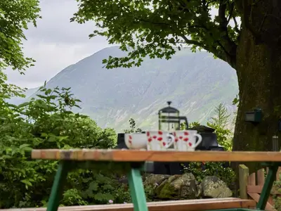 two mugs on a picnic table with a view of a mountain at 2 Bed in Cockermouth oc-sz588 in Buttermere