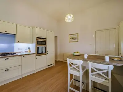 a kitchen with white cabinets and a island with bar stools at 4 Bed in Ambleside oc-85294 in Grasmere