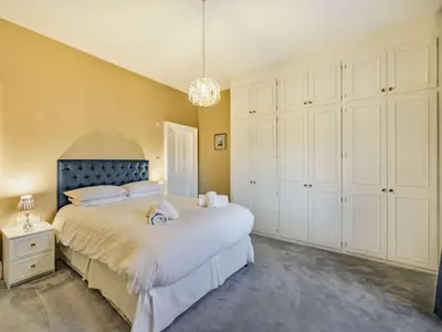 a bedroom with a bed with white cabinets and a chandelier at 4 Bed in Ambleside oc-85294 in Grasmere